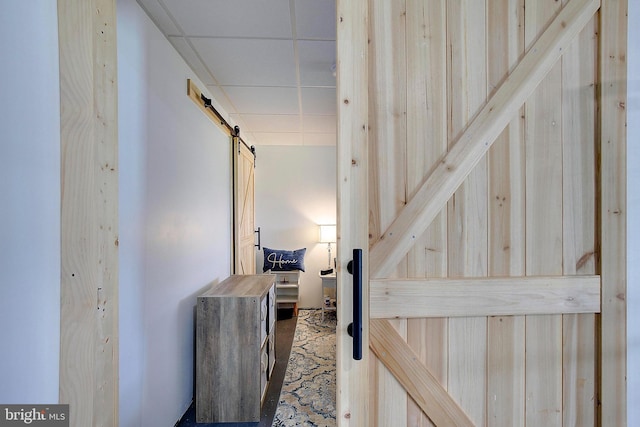 corridor featuring a drop ceiling and a barn door