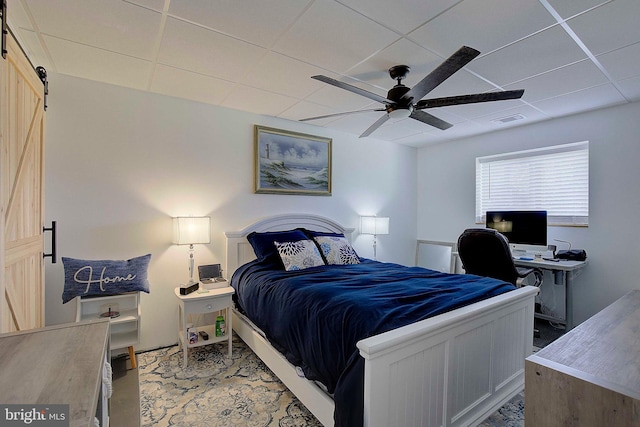 bedroom featuring a barn door, ceiling fan, and a paneled ceiling