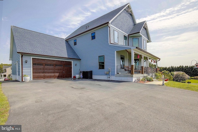 view of front of house featuring a porch, a garage, and central air condition unit