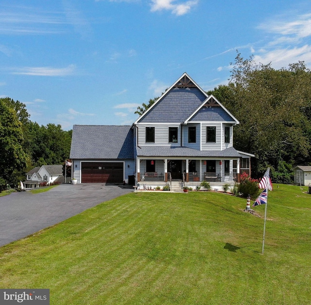 view of front of property featuring covered porch, a garage, and a front yard