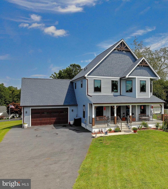 view of front of home featuring a front lawn, covered porch, and a garage