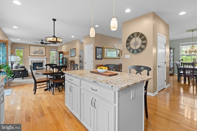 kitchen featuring white cabinets, a center island, hanging light fixtures, and ceiling fan