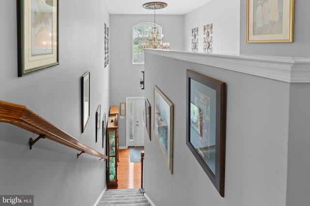 stairway featuring wood-type flooring and a notable chandelier