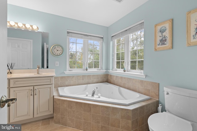 bathroom featuring vanity, toilet, and tiled bath