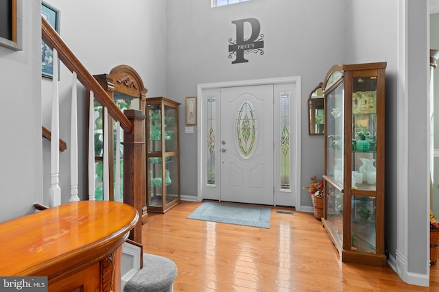 entryway featuring a towering ceiling, light hardwood / wood-style floors, and a healthy amount of sunlight