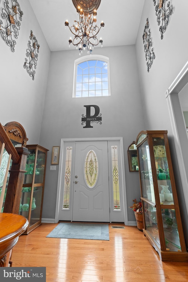 foyer featuring hardwood / wood-style floors, a towering ceiling, and an inviting chandelier