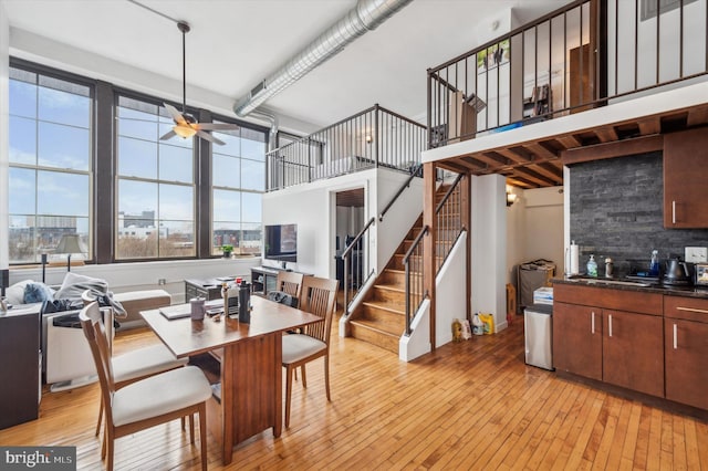 dining space featuring ceiling fan, light wood-type flooring, a high ceiling, and a wealth of natural light