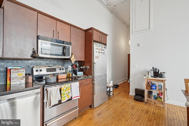 kitchen with appliances with stainless steel finishes, light wood-type flooring, and tasteful backsplash