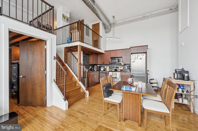 dining area featuring light hardwood / wood-style floors and a towering ceiling