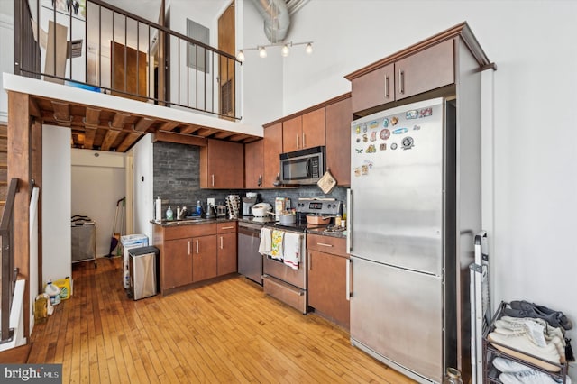 kitchen with decorative backsplash, light hardwood / wood-style flooring, and appliances with stainless steel finishes