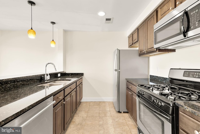 kitchen featuring pendant lighting, sink, appliances with stainless steel finishes, and dark stone counters