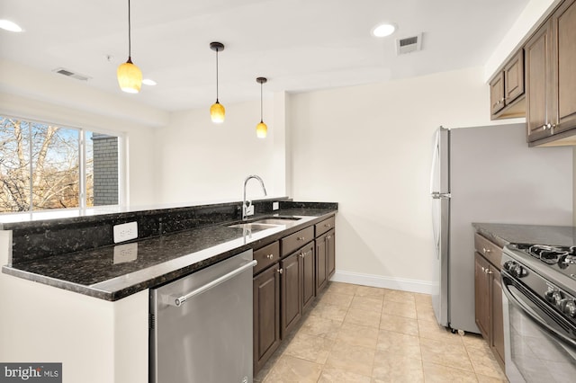 kitchen with decorative light fixtures, dark stone countertops, sink, and stainless steel appliances