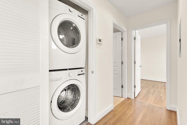 clothes washing area with light hardwood / wood-style floors and stacked washer / dryer