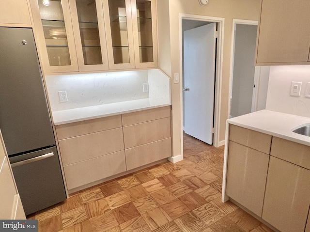 kitchen featuring light parquet floors, sink, stainless steel refrigerator, and cream cabinetry