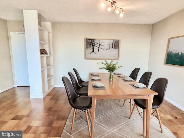 dining space with hardwood / wood-style flooring, a textured ceiling, and built in shelves