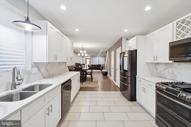 kitchen with sink, light hardwood / wood-style flooring, decorative light fixtures, white cabinets, and appliances with stainless steel finishes