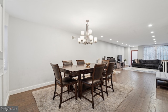 dining space featuring dark hardwood / wood-style floors and an inviting chandelier