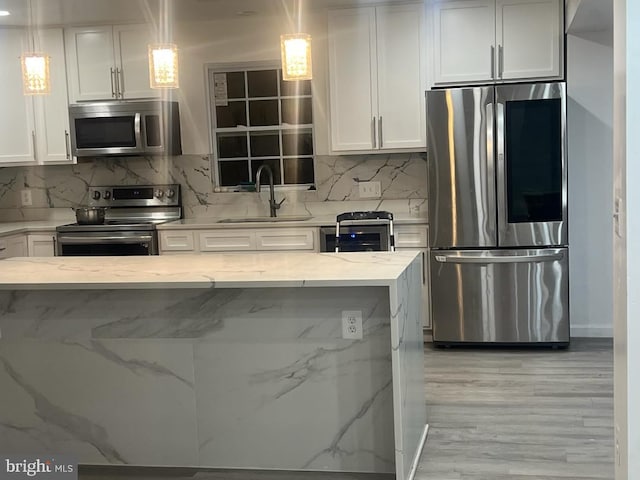 kitchen with white cabinets, stainless steel appliances, and decorative light fixtures