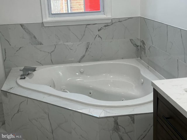 bathroom with vanity and tiled tub