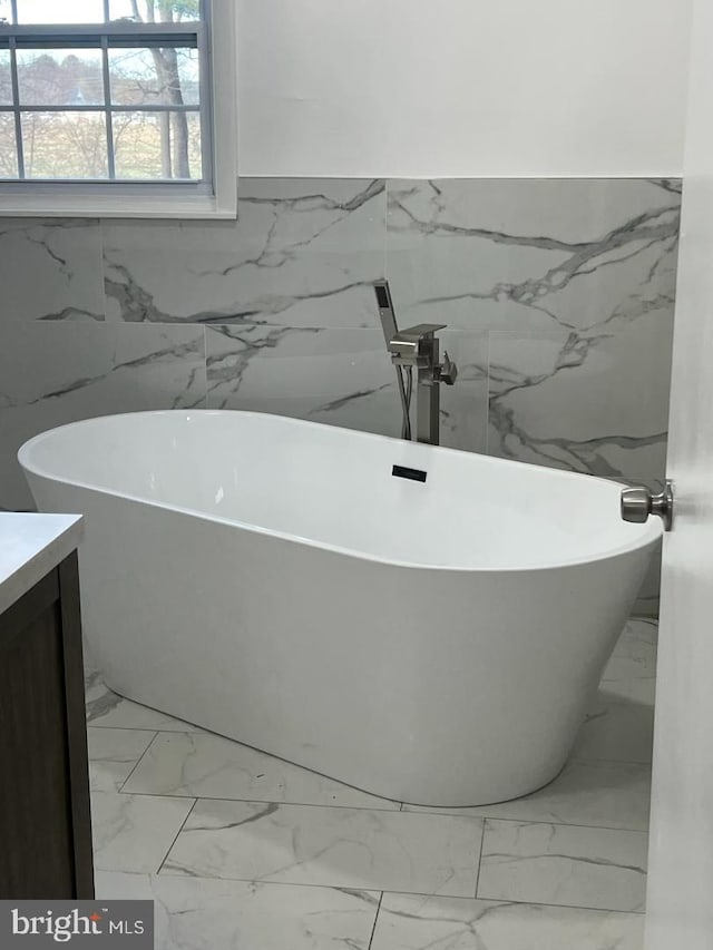 bathroom featuring a washtub, vanity, and tile walls