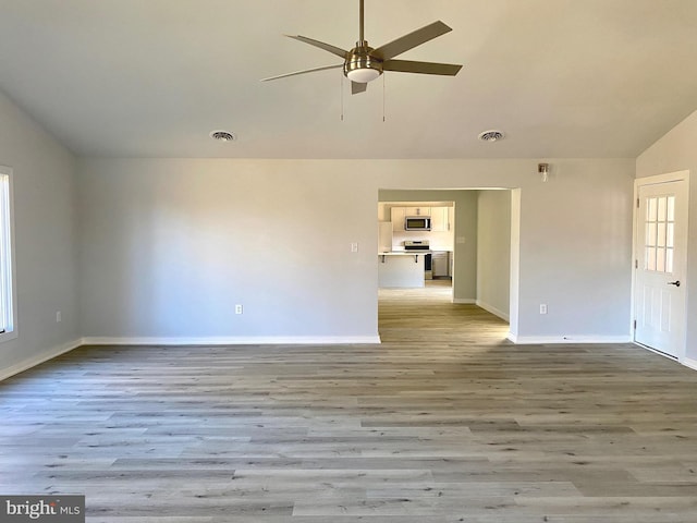 empty room featuring ceiling fan, vaulted ceiling, and light hardwood / wood-style flooring