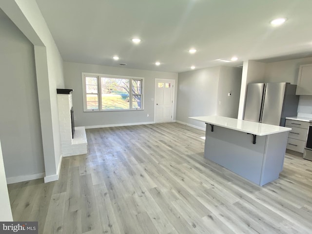 unfurnished living room featuring light wood-type flooring and a brick fireplace