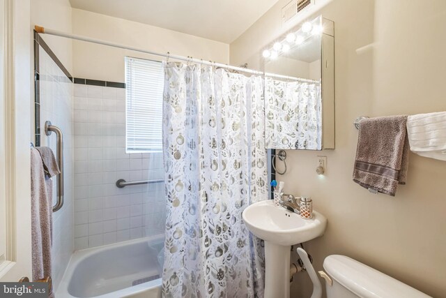 bathroom featuring toilet and shower / tub combo with curtain