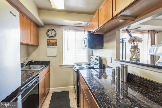 kitchen with light tile patterned floors, sink, dark stone counters, and black appliances