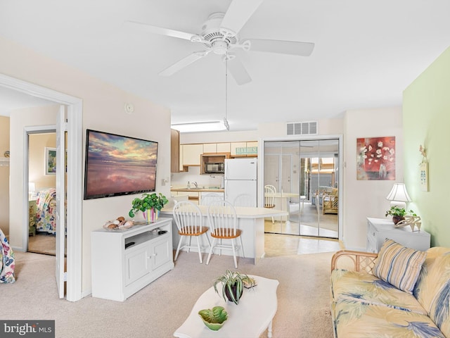 carpeted living room featuring ceiling fan and sink