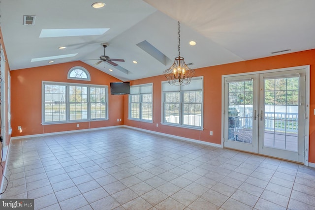 tiled spare room with vaulted ceiling with skylight, ceiling fan with notable chandelier, a wealth of natural light, and french doors