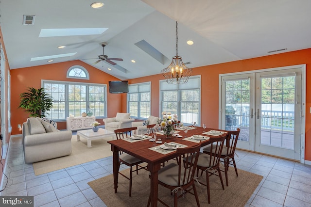 dining space featuring light tile patterned floors, ceiling fan with notable chandelier, lofted ceiling with skylight, and french doors