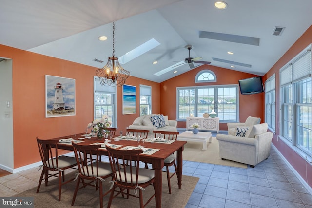 tiled dining space with ceiling fan with notable chandelier, vaulted ceiling, and a healthy amount of sunlight