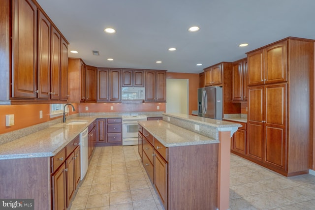 kitchen with white appliances, sink, light stone countertops, light tile patterned floors, and a kitchen island