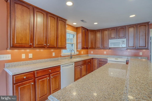 kitchen with white appliances, light stone counters, and sink