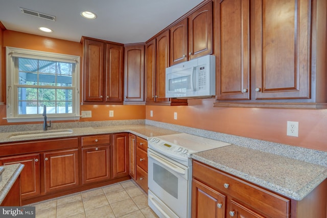 kitchen featuring light stone countertops, light tile patterned floors, white appliances, and sink