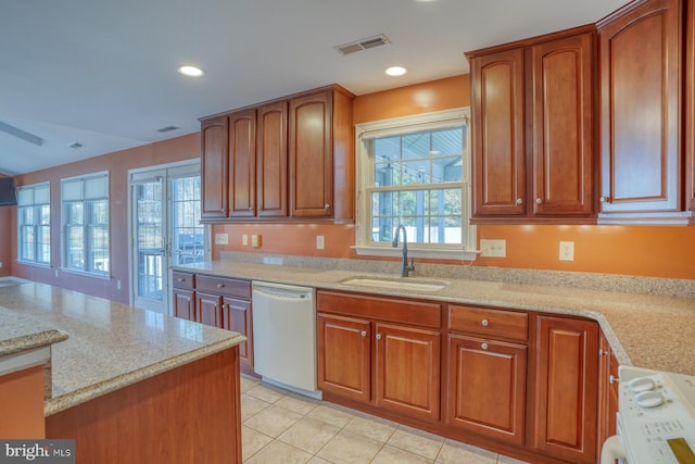 kitchen featuring light stone countertops, white appliances, light tile patterned flooring, and sink