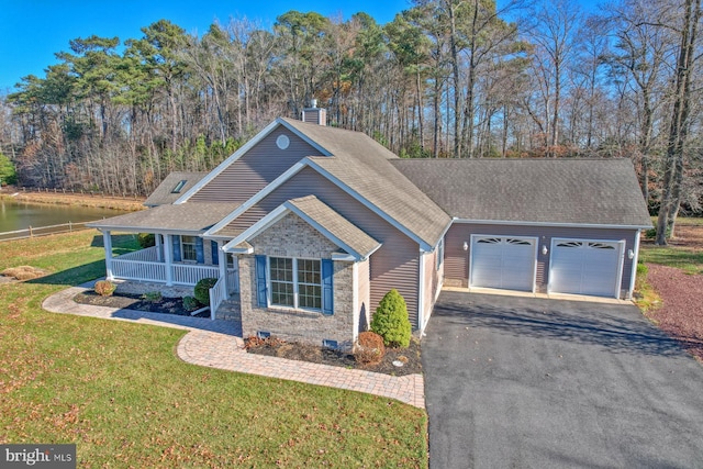 view of front of property with a water view, a front lawn, covered porch, and a garage