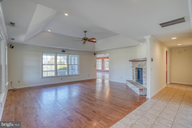 unfurnished living room with ceiling fan, light hardwood / wood-style floors, ornamental molding, and a brick fireplace