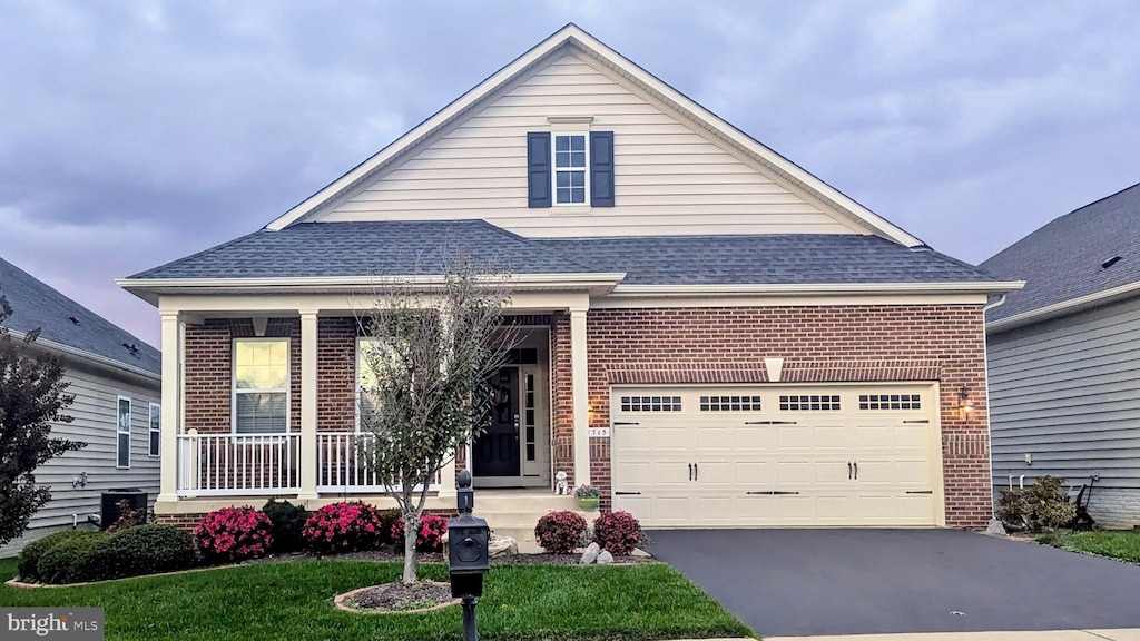 view of front of property with covered porch, a shingled roof, aphalt driveway, and brick siding