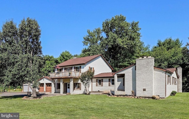 back of property featuring a wooden deck, a garage, an outdoor structure, and a lawn