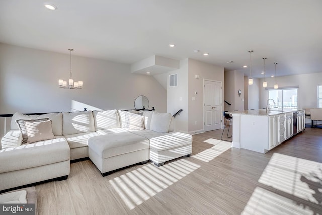 living room featuring sink, light hardwood / wood-style flooring, and an inviting chandelier