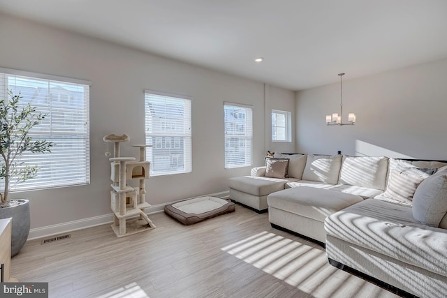 living room featuring light hardwood / wood-style floors, a chandelier, and plenty of natural light