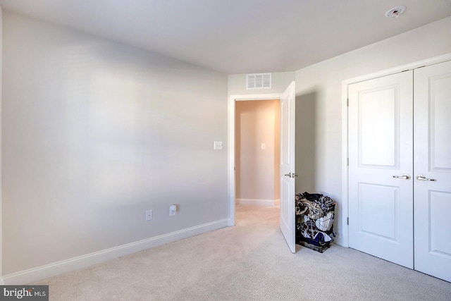 unfurnished bedroom featuring light colored carpet and a closet