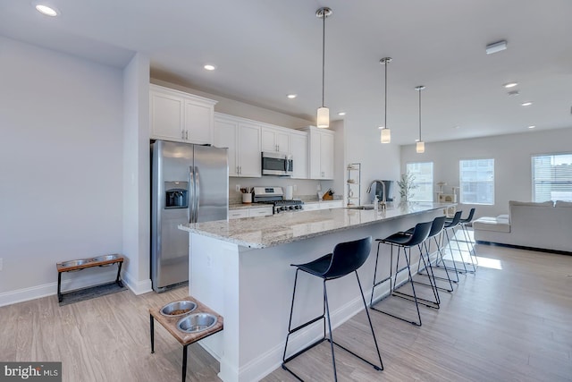 kitchen with hanging light fixtures, a large island, white cabinets, sink, and stainless steel appliances