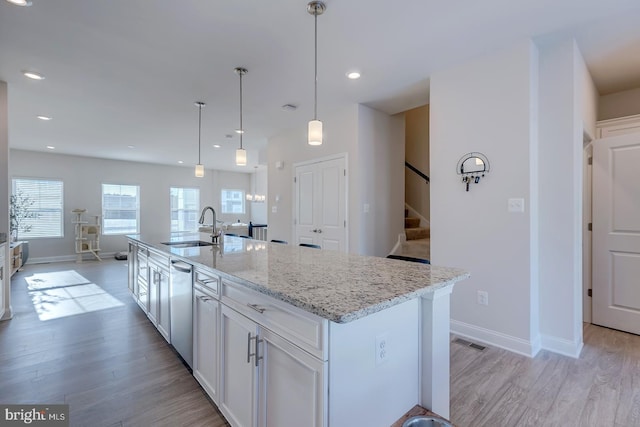 kitchen with sink, white cabinetry, a kitchen island with sink, and hanging light fixtures