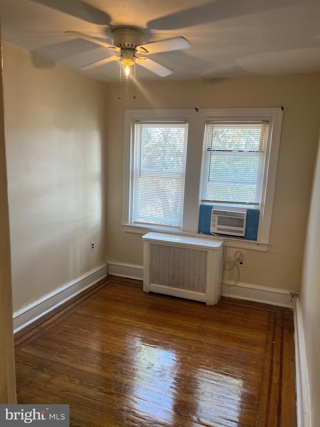 empty room featuring cooling unit, dark wood-type flooring, ceiling fan, and radiator