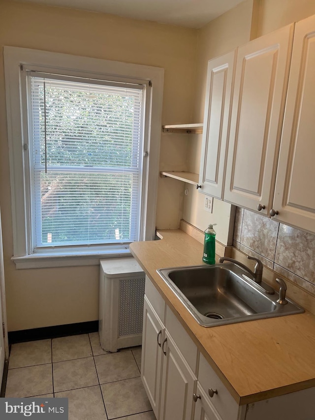 kitchen featuring white cabinets, plenty of natural light, sink, and light tile patterned floors