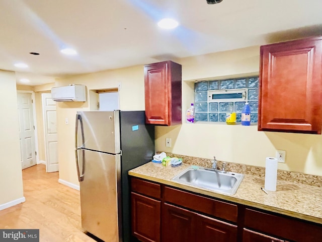 kitchen featuring sink, light hardwood / wood-style floors, a wall mounted air conditioner, and stainless steel fridge