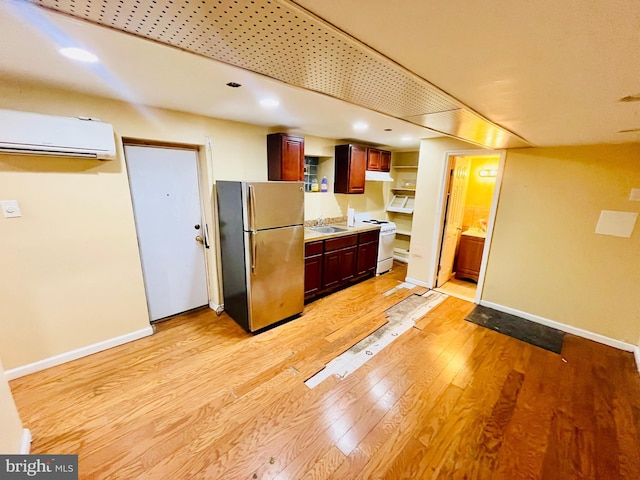 kitchen with a wall unit AC, stainless steel fridge, light wood-type flooring, white electric stove, and sink