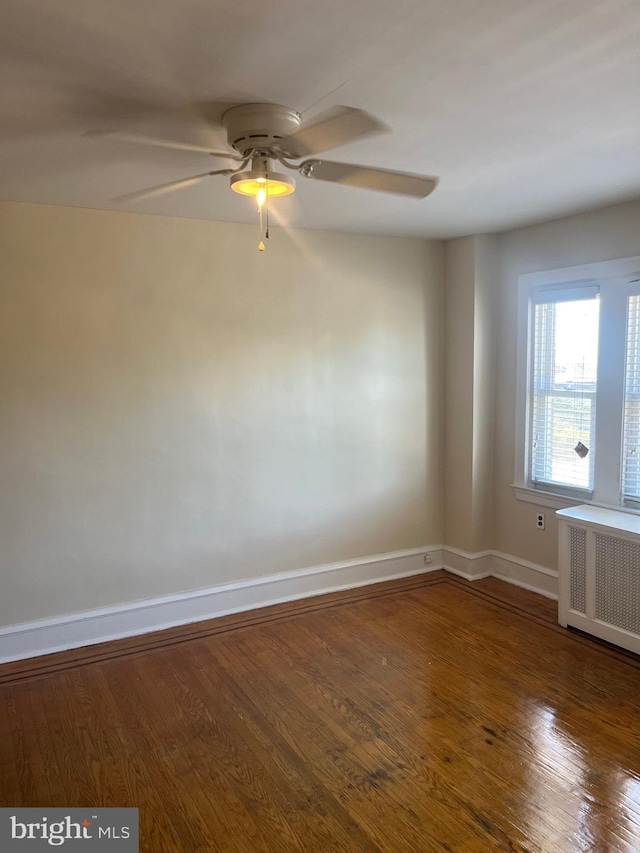 unfurnished room with ceiling fan, radiator heating unit, and dark hardwood / wood-style floors